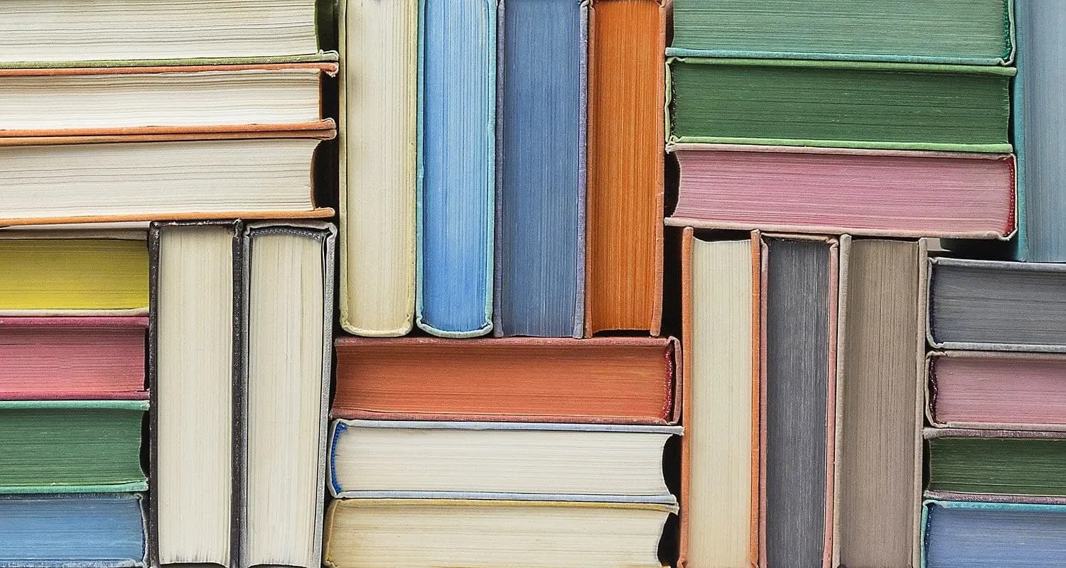 Stacks of colourful hardback books arranged so their page edges face outward