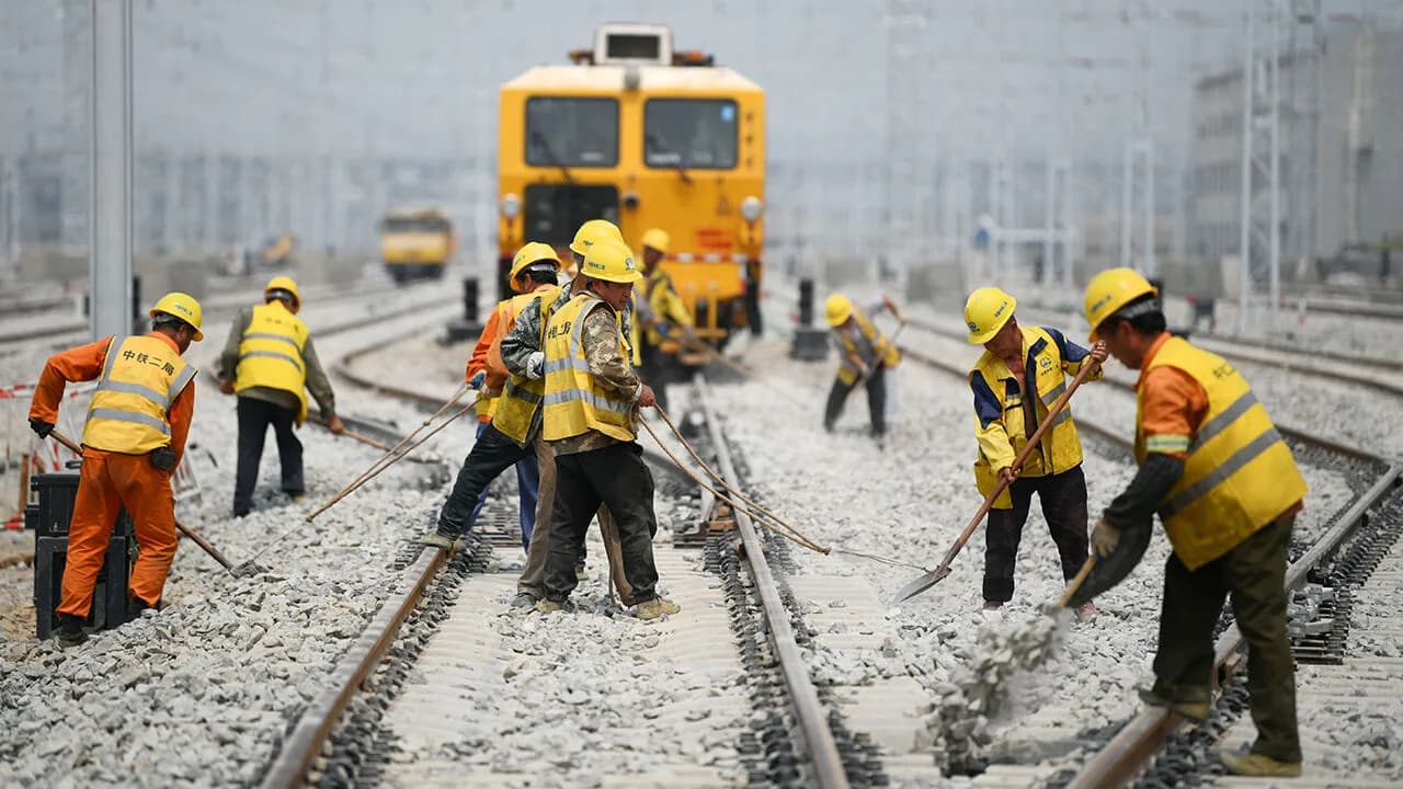 Workers laying and maintaining railway track at a rail yard in China