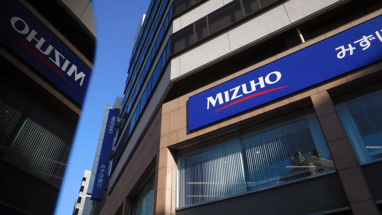 A Mizuho bank branch sign on an office building in Tokyo under a blue sky