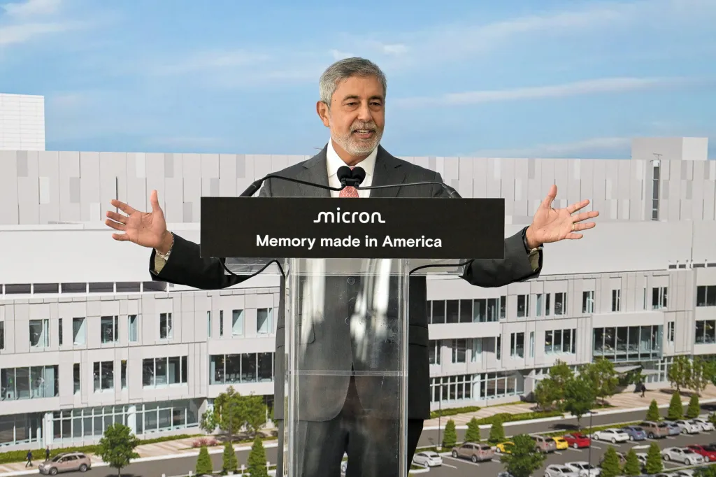 A Micron executive speaks at a podium reading Memory made in America in front of a chip factory