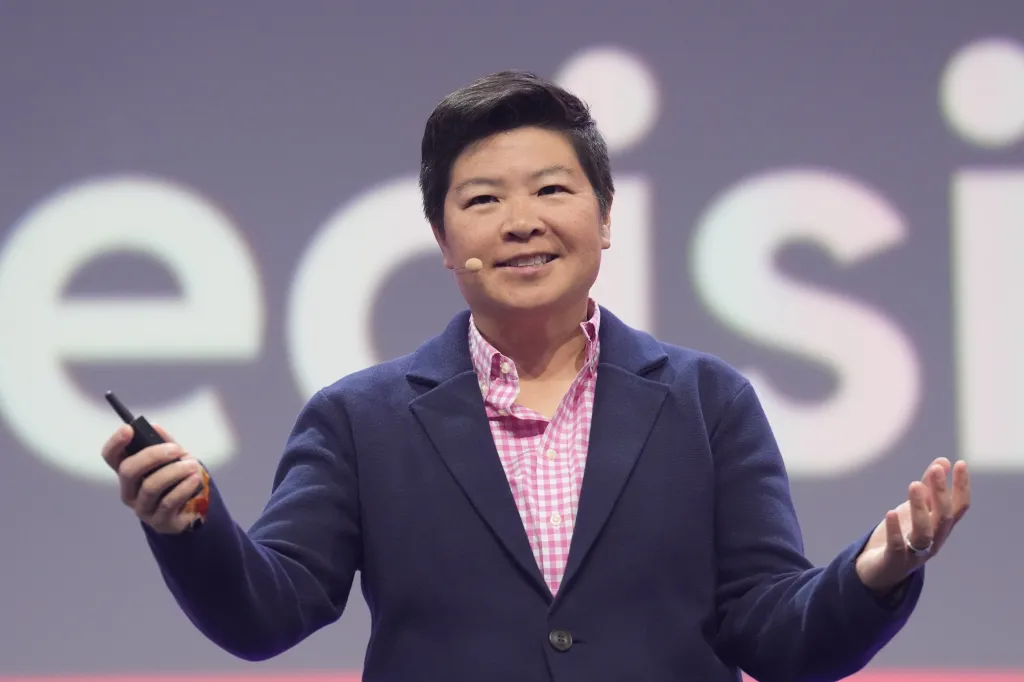 Reddit chief operating officer Jen Wong gestures while speaking on stage with a presentation remote in hand