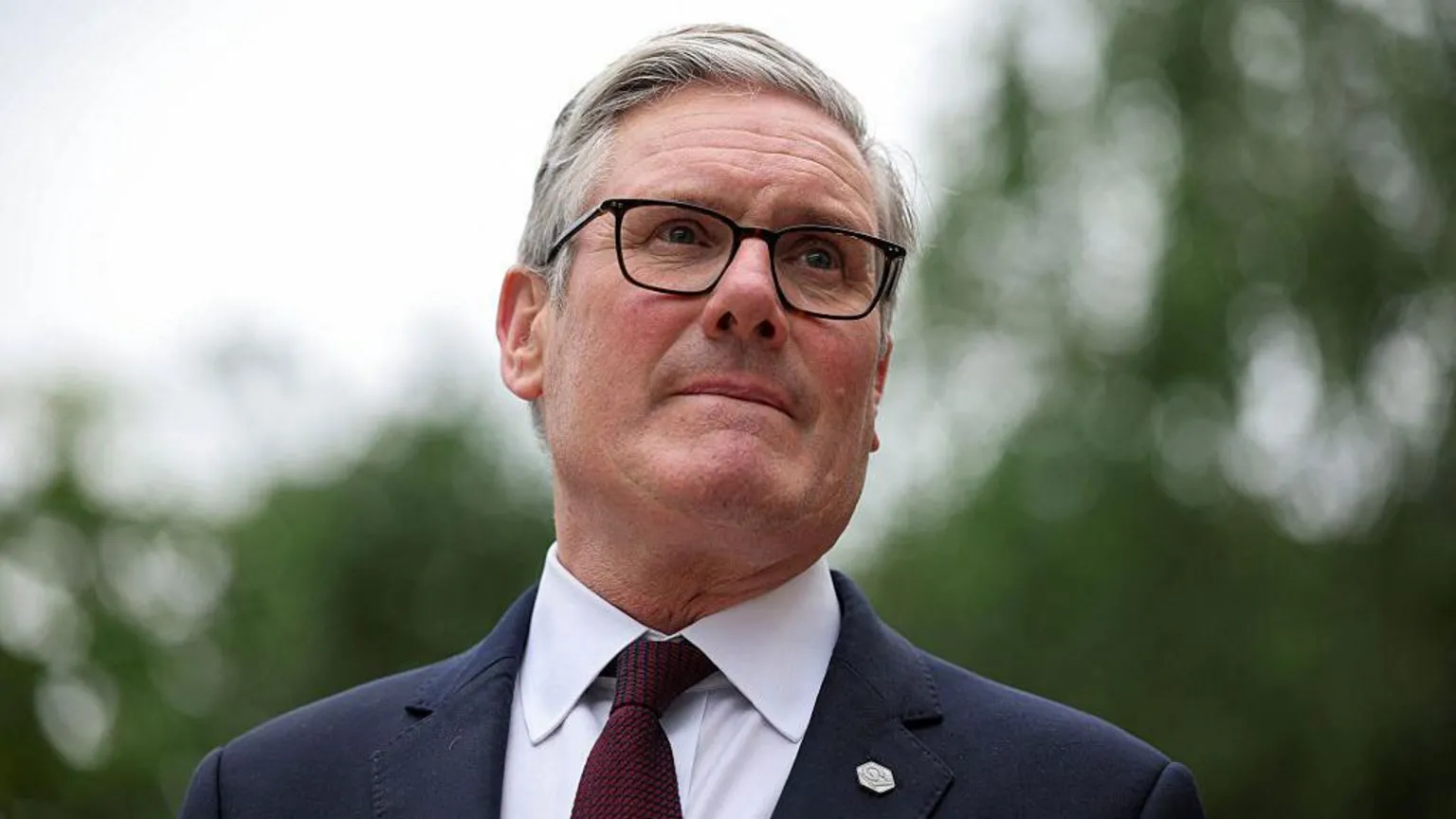 Sir Keir Starmer in glasses and a dark suit standing outdoors