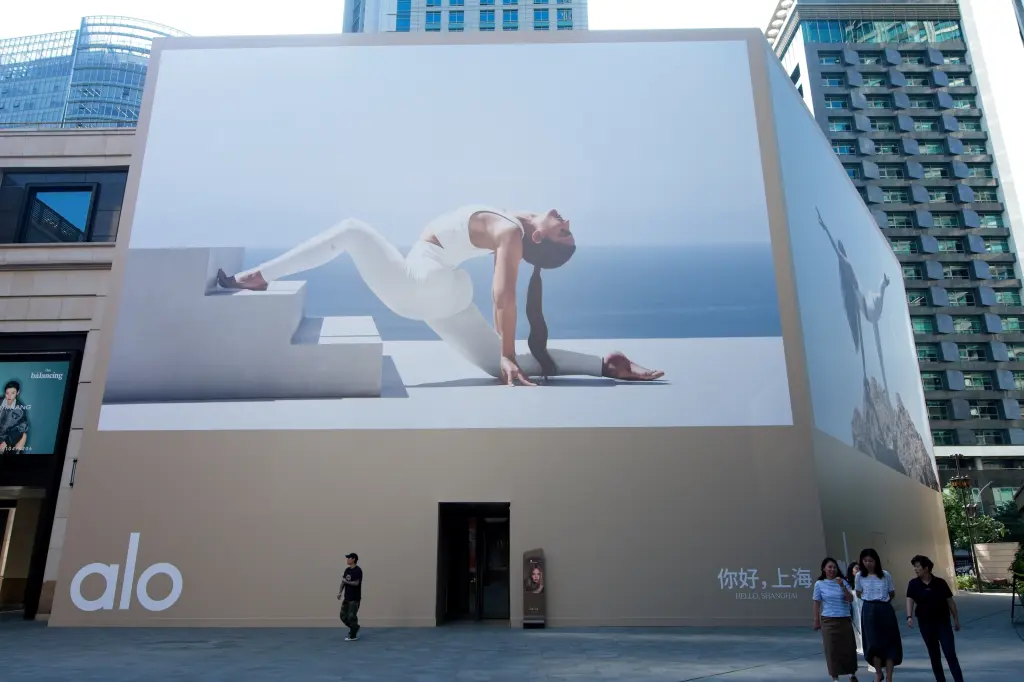 A large Alo storefront billboard featuring a yoga pose towers over a Shanghai street