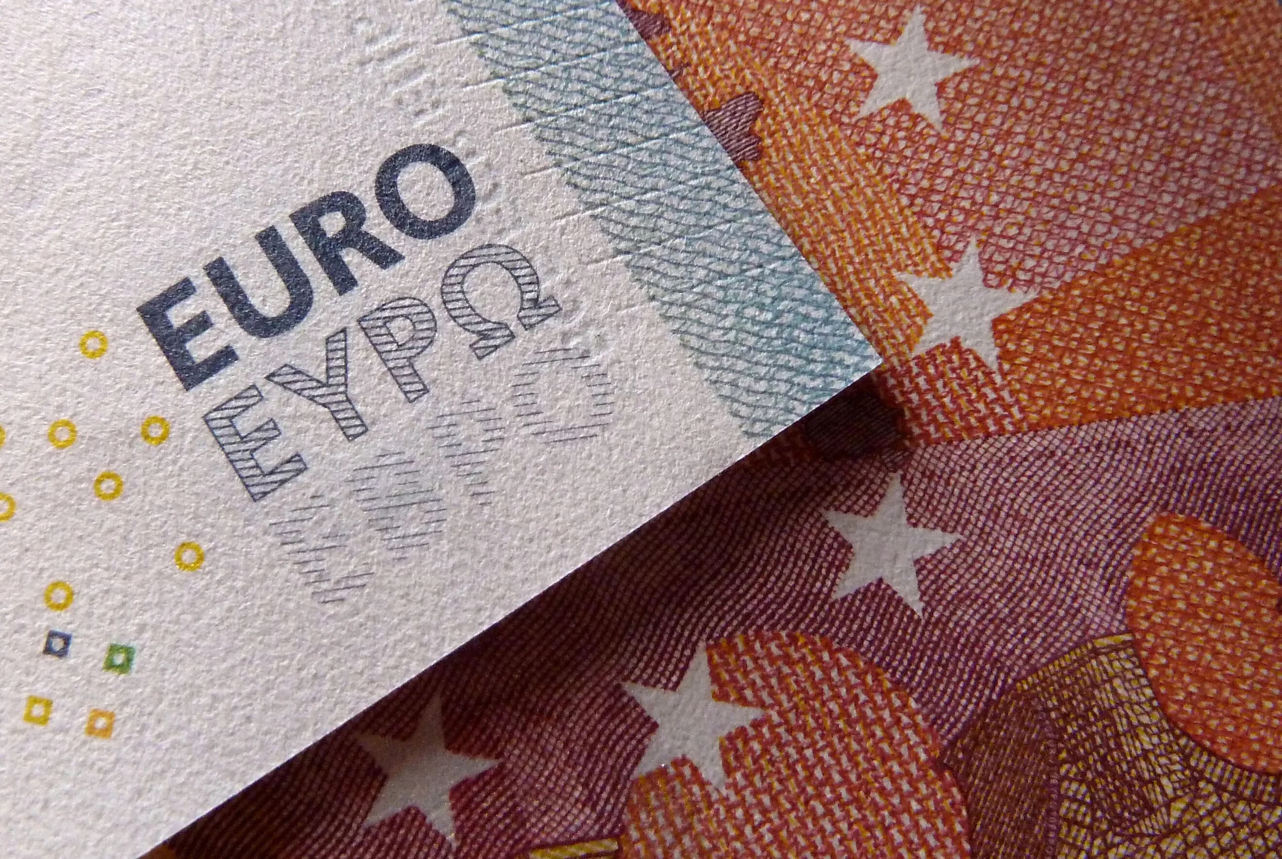 Close up of euro banknotes overlapping, showing the word EURO and the EU stars