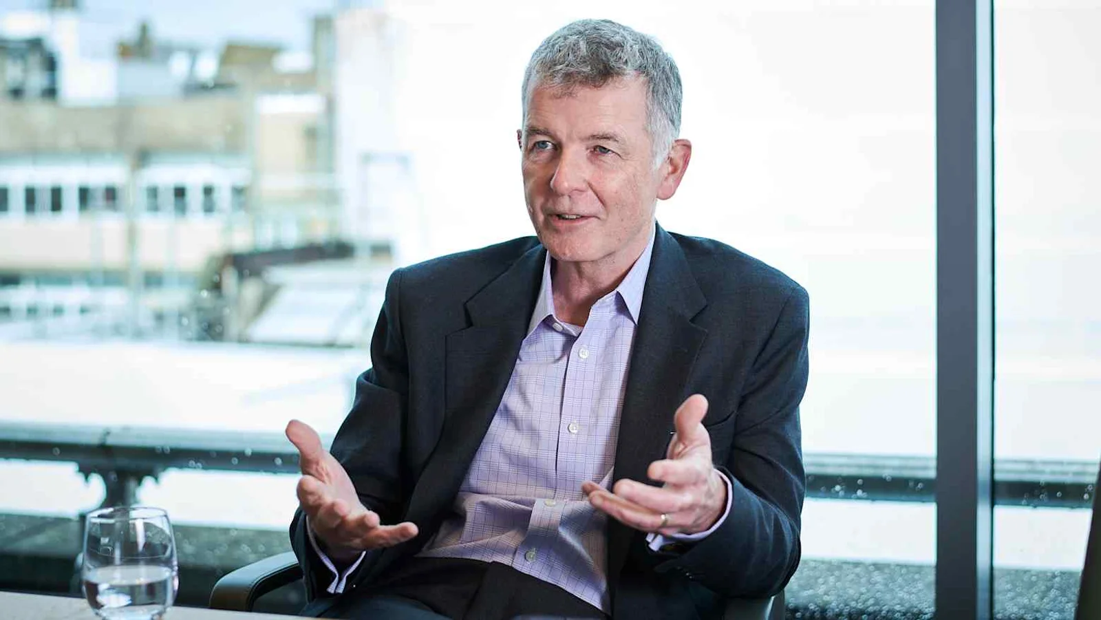 Richard Moore, former head of Britain's MI6, gestures with both hands while speaking during an interview beside a bright window