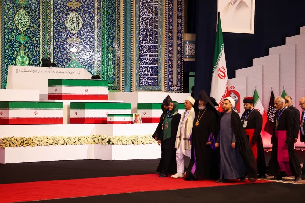 Representatives of Iran's religious minorities walk past flag draped coffins at the state funeral for Ayatollah Ali Khamenei in Tehran
