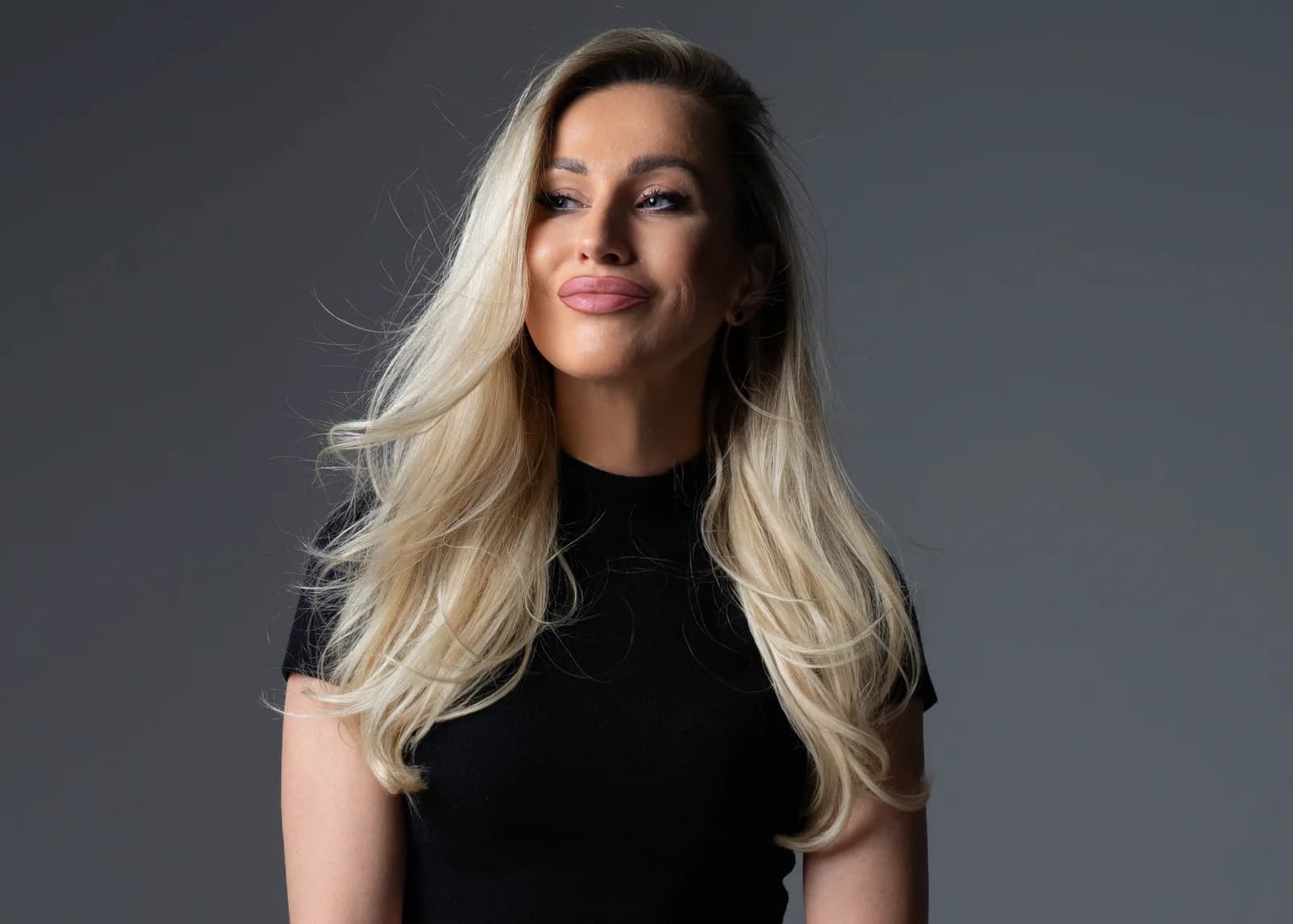 Studio portrait of Irina Biss with long blonde hair in a black top against a grey background