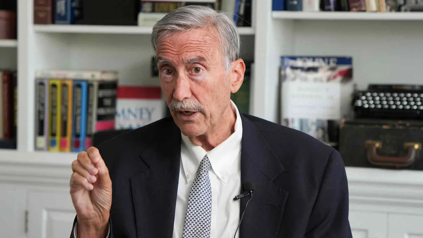 Political scientist Larry Sabato gestures while speaking during an interview in front of bookshelves and a vintage typewriter