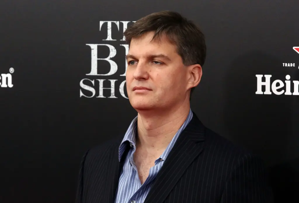 Michael Burry in a pinstripe suit stands in front of a black step-and-repeat backdrop for The Big Short