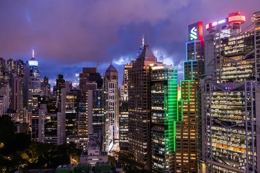 A night skyline of illuminated skyscrapers in a major Asian financial district